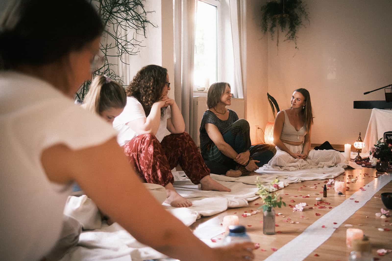 Ein Kreis von Frauen sitzt bei Kerzenlicht auf dem Boden im Haus der Monde